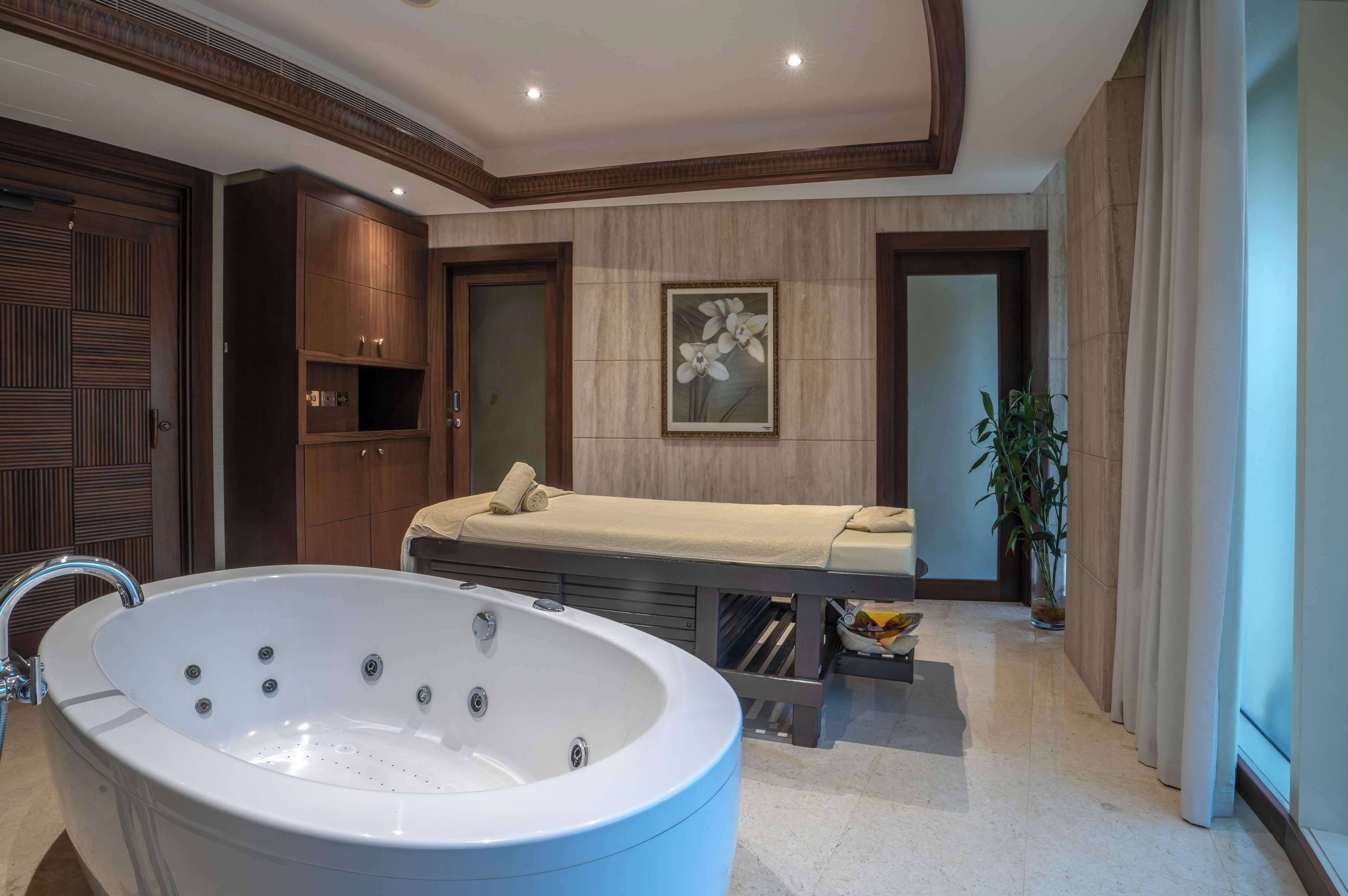 A modern bathroom with a large bathtub, a massage table, and a wooden cabinet.