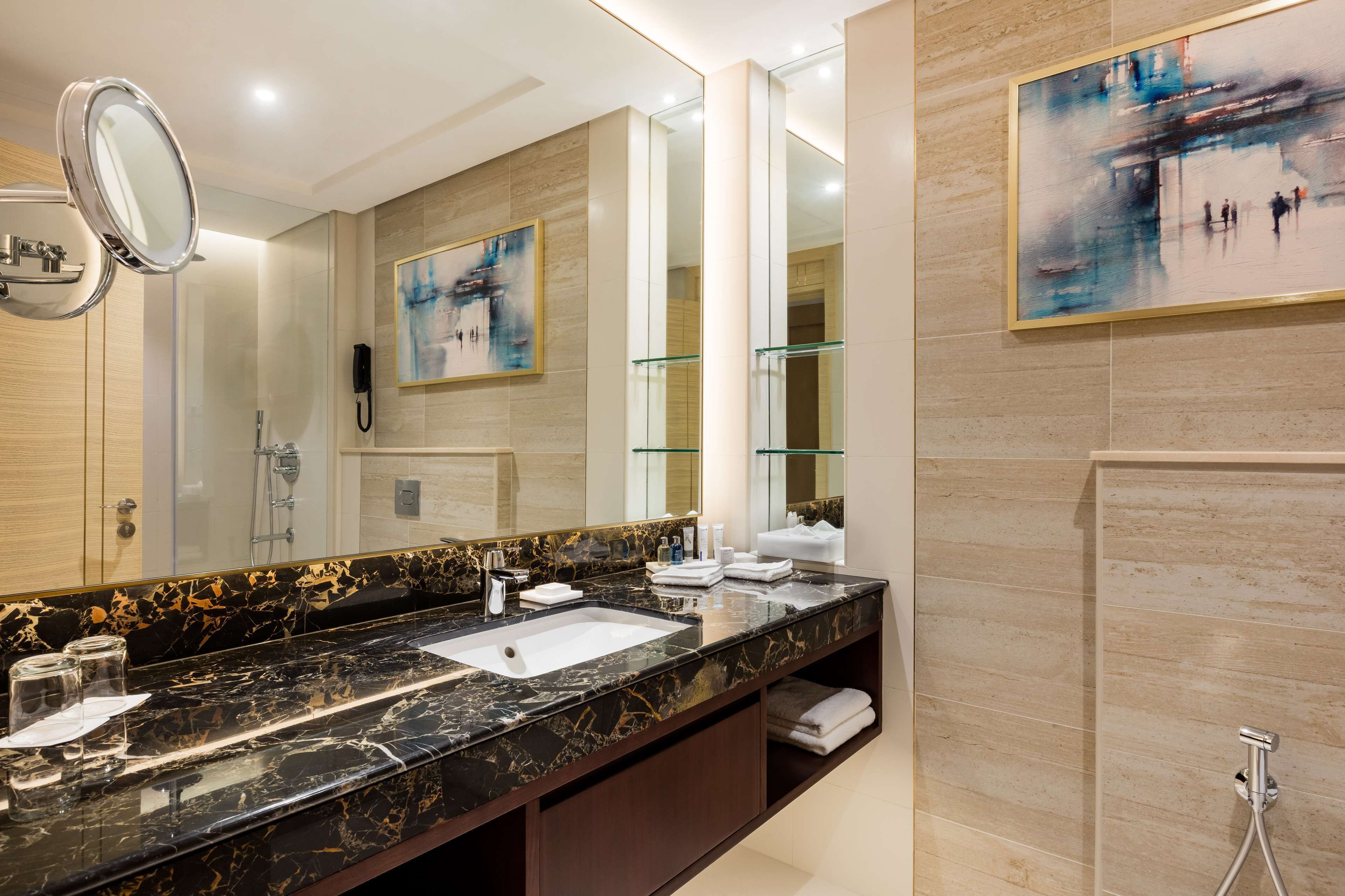 Un baño moderno con lavamanos de mármol, espejos grandes y cabina de ducha de vidrio.