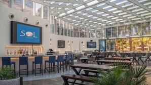 A modern bar area with a glass ceiling, bar stools, and a counter with a branded sign. - The Diplomat Radisson BLU Hotel, Residence & Spa (Manama)