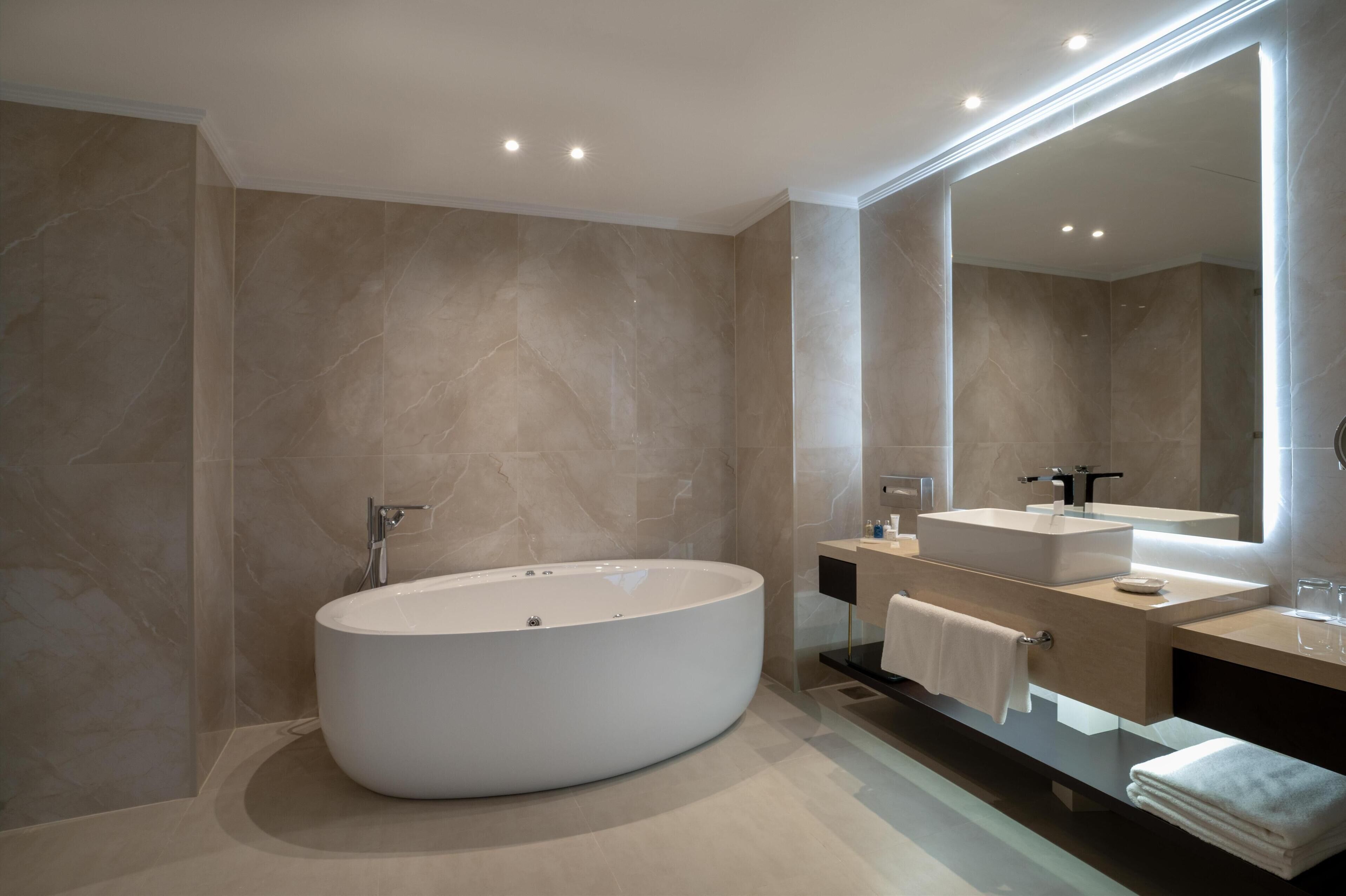 Une salle de bain moderne avec une baignoire sur pieds, un meuble-lavabo avec un miroir et un grand miroir au-dessus du lavabo.
