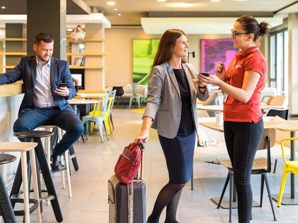 A modern indoor space with seating arrangements, tables, and a person interacting with another individual.