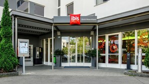 An ibis hotel entrance with a covered entrance, glass doors, and a sign indicating it's located at Zürich Messe-Airport. - ibis Zurich Messe-Airport (Zürich)