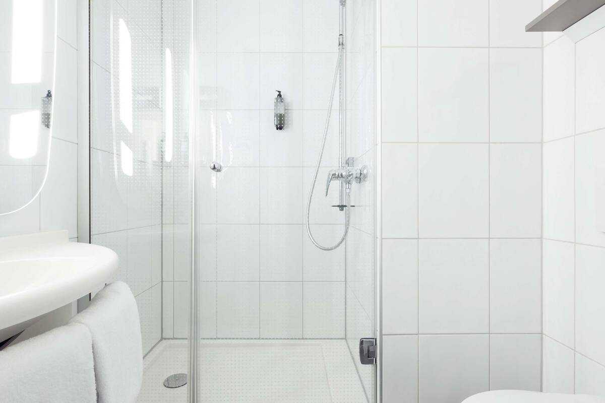 A modern bathroom with a glass-enclosed shower, a white sink, and a toilet.