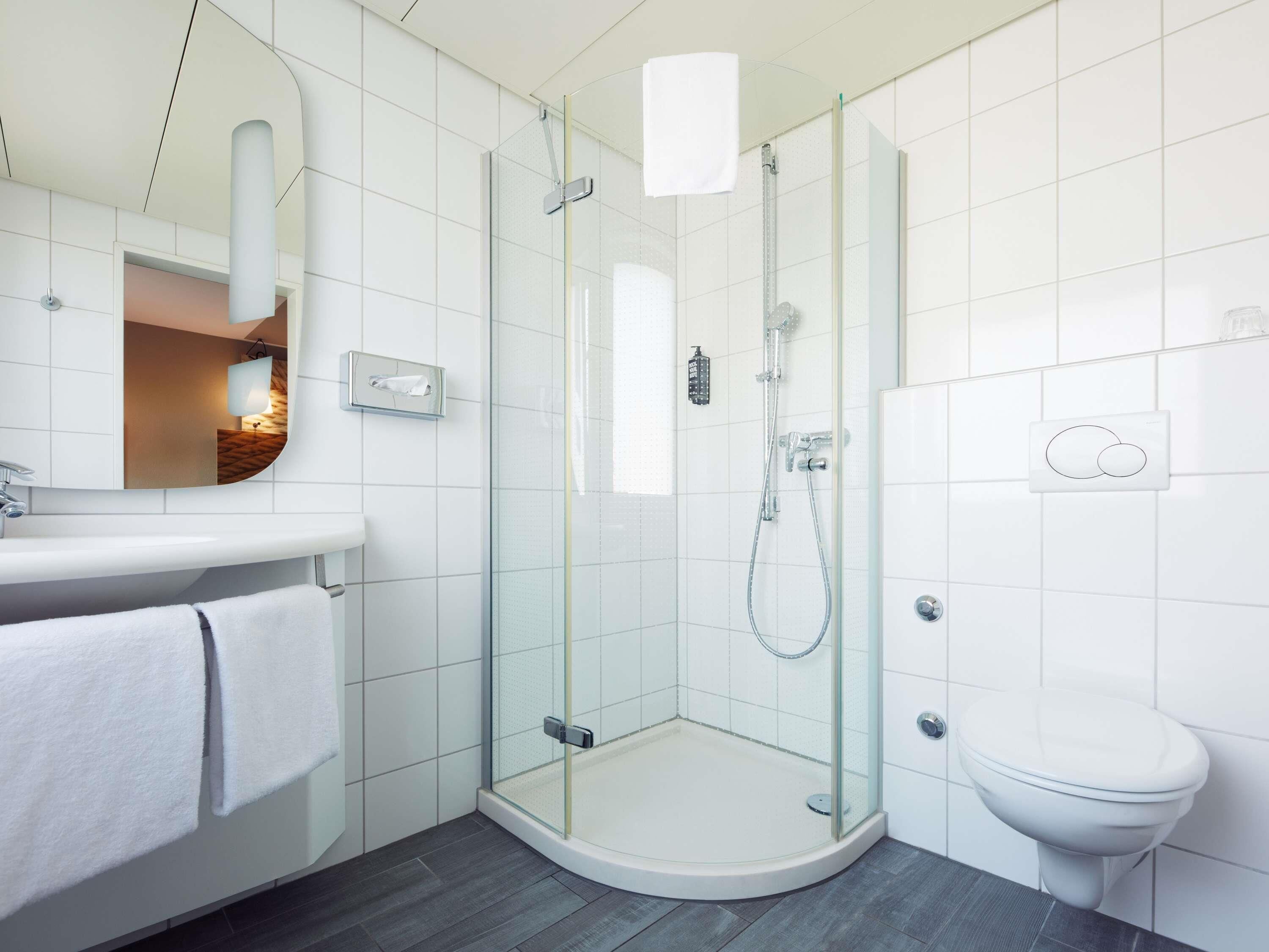 A modern bathroom with a glass-enclosed shower, a white toilet, and a vanity with a mirror.