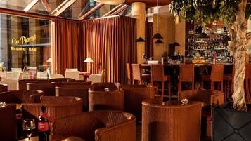 A cozy bar area with wicker chairs, a bar counter, and a large tree.