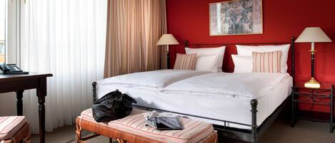 Une chambre d’hôtel avec un grand lit, deux lampes de chevet, un bureau avec un téléphone et une chaise.