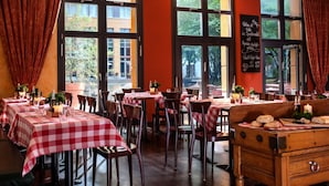 Un interior de restaurante con manteles a cuadros, sillas de madera y una pizarra con el menú.