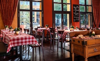 A restaurant interior with checkered tablecloths, wooden chairs, and a chalkboard menu.