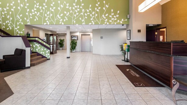 Un vestíbulo amplio con una escalera, un mostrador de recepción y una pared verde con motivos florales blancos.