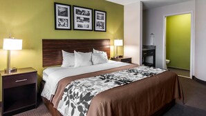 Habitación de hotel con una cama, dos mesitas de noche con lámparas, un cabecero, una pared verde decorativa y cuadros enmarcados.