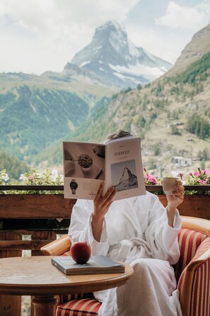 Una persona leyendo un libro con vistas a la montaña.