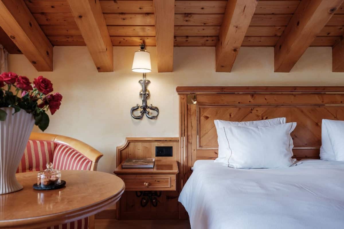 A wooden room with a bed, a nightstand, a chair, and a table.