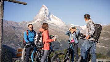 A group of people with bicycles near a mountain with a prominent peak.