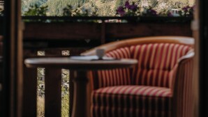 A view of a mountain from a room with a striped chair and a table. - Relais & Chateaux Schönegg (Zermatt)