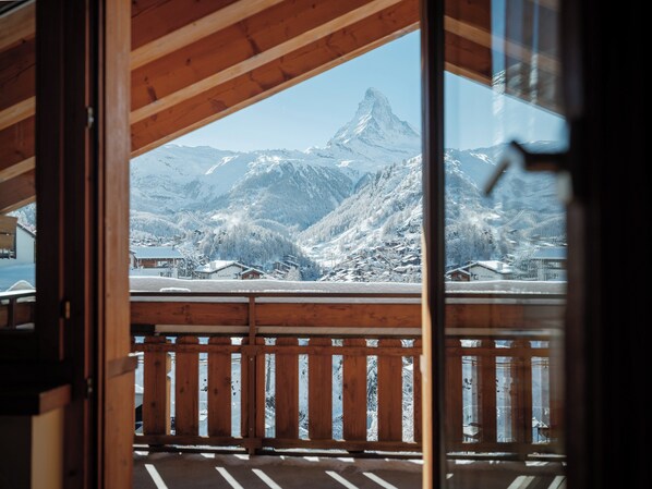 A wooden balcony with a view of snow-covered mountains and a prominent peak. - Relais & Chateaux Schönegg (Zermatt)