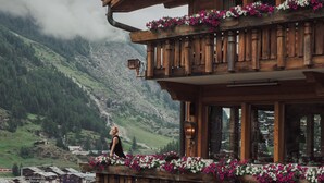 A wooden chalet with balconies adorned with flowers, set against a mountainous backdrop. - Relais & Chateaux Schönegg (Zermatt)