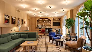 Een moderne woonkamer met een bank, stoelen, een salontafel en een boekenkast.