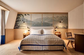 A bedroom with a bed, two bedside tables, a chair, a desk, and a large wall mural. - Sorell Boutique-Hotel Speer Rapperswil (Rapperswil-Jona)