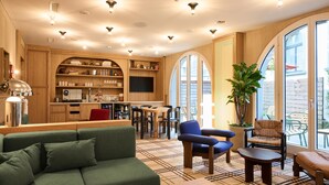 A modern interior with a sofa, chairs, a coffee table, a kitchen area, and large windows. - Sorell Boutique-Hotel Speer Rapperswil (Rapperswil-Jona)