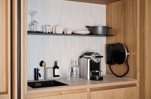 Eine moderne Küche mit integrierter Kaffeemaschine, Wasserkocher und einer Weinflasche auf der Arbeitsplatte.
