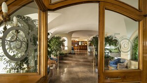 A hotel lobby with a grand staircase, wooden furniture, and a reception desk. - Hotel Continental Ischia (Ischia)