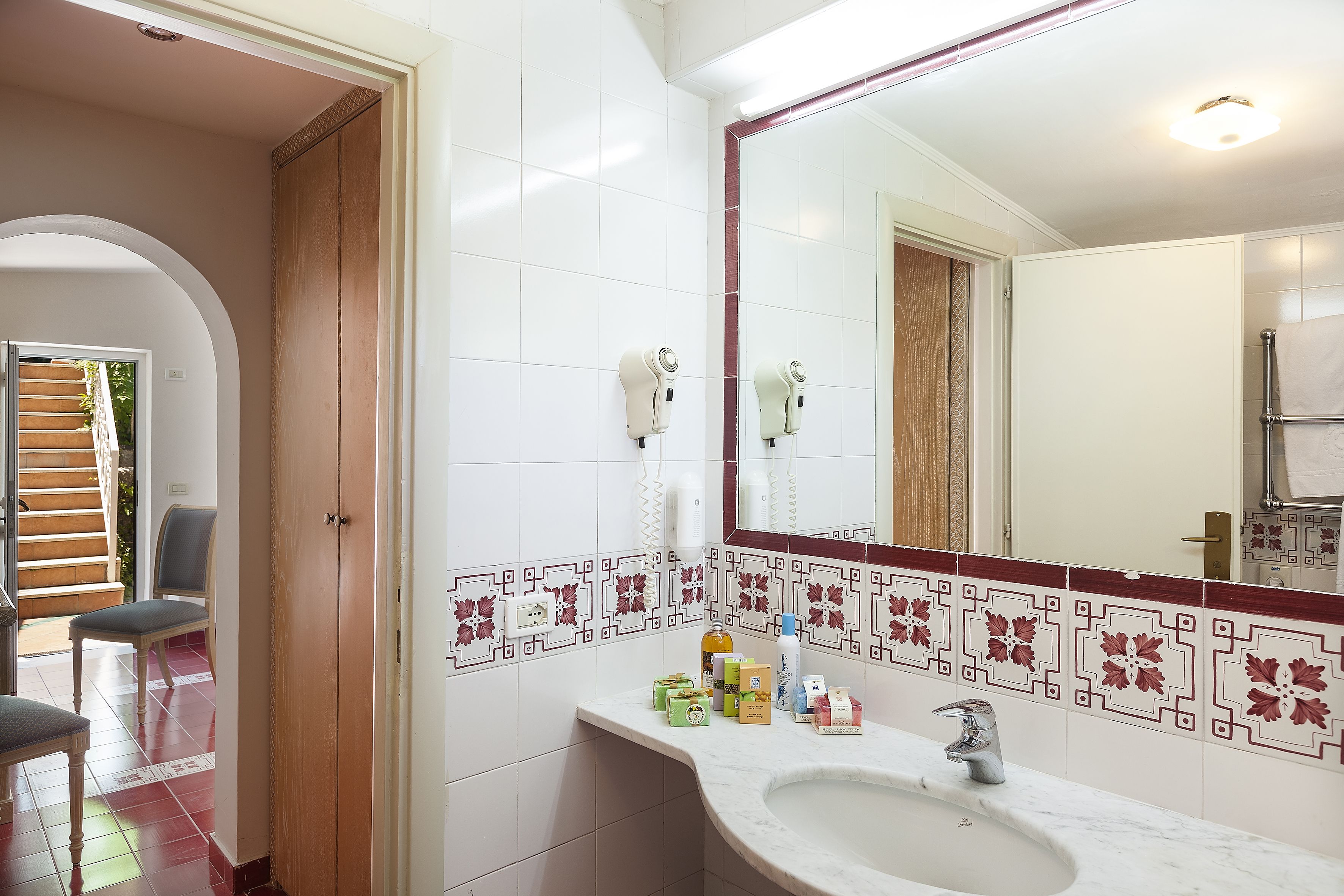 A bathroom with a sink, mirror, and hair dryers on the wall.
