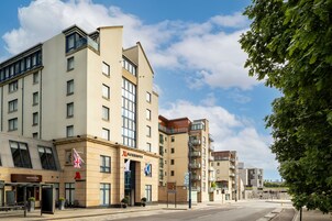Un hotel moderno con fachada plana, varios balcones y cielo despejado.