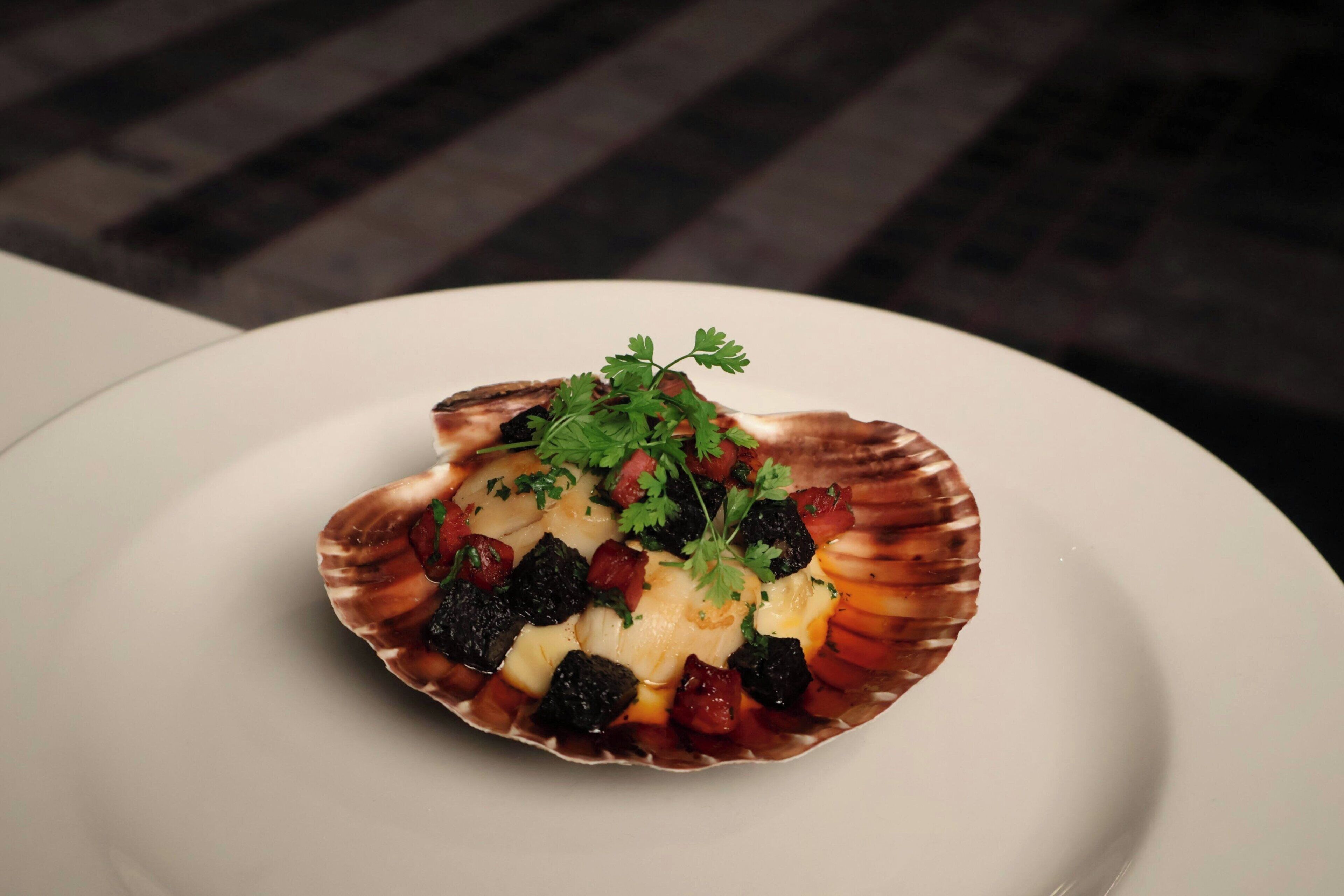A scallop dish on a white plate.
