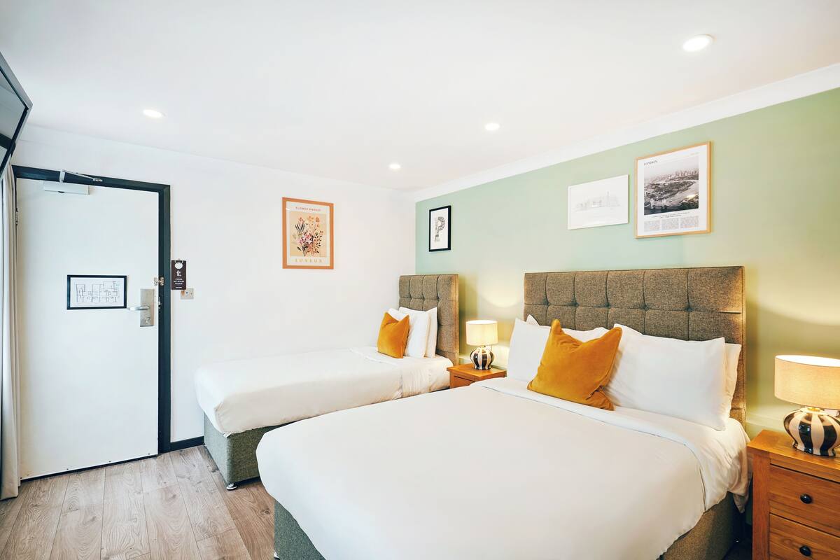 Une chambre d’hôtel avec deux lits, une porte et des œuvres d’art accrochées au mur.