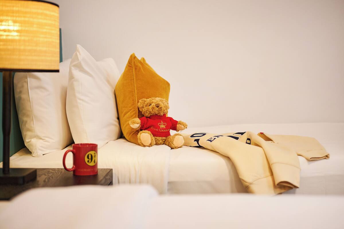 Un lit avec un ours en peluche, une tasse rouge et une lampe.