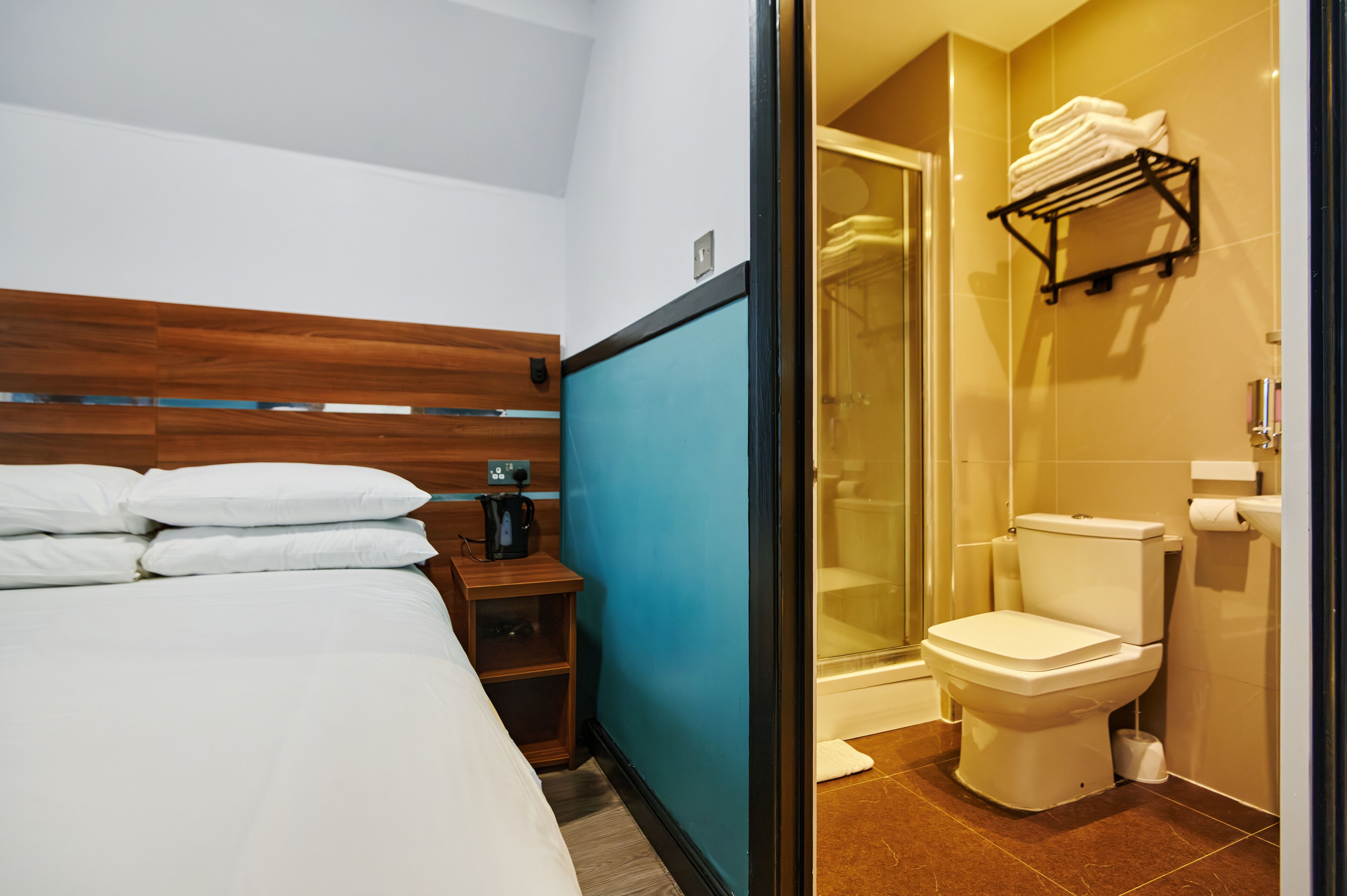 Ein Hotelzimmer mit Bett, Nachttisch, Kaffeemaschine, Dusche und Toilette.