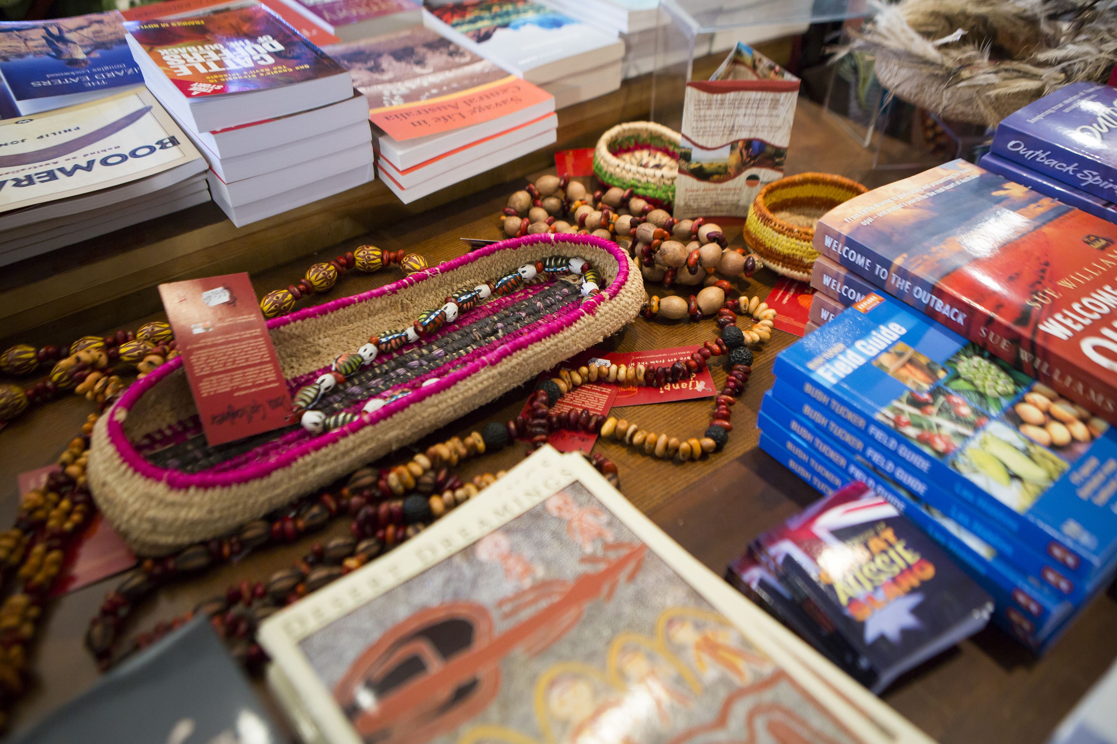Una mesa con diversos objetos, incluyendo libros, joyería de cuentas y cestas tejidas.