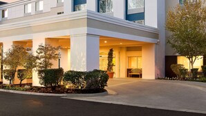A modern hotel with a white facade, large windows, and a welcoming entrance.