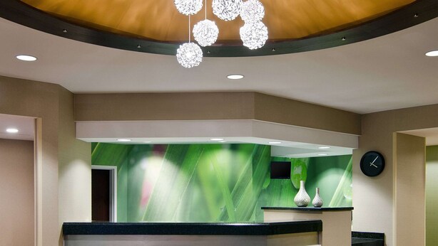 A reception area with a wooden ceiling, a reception desk, and a green wall with a clock.