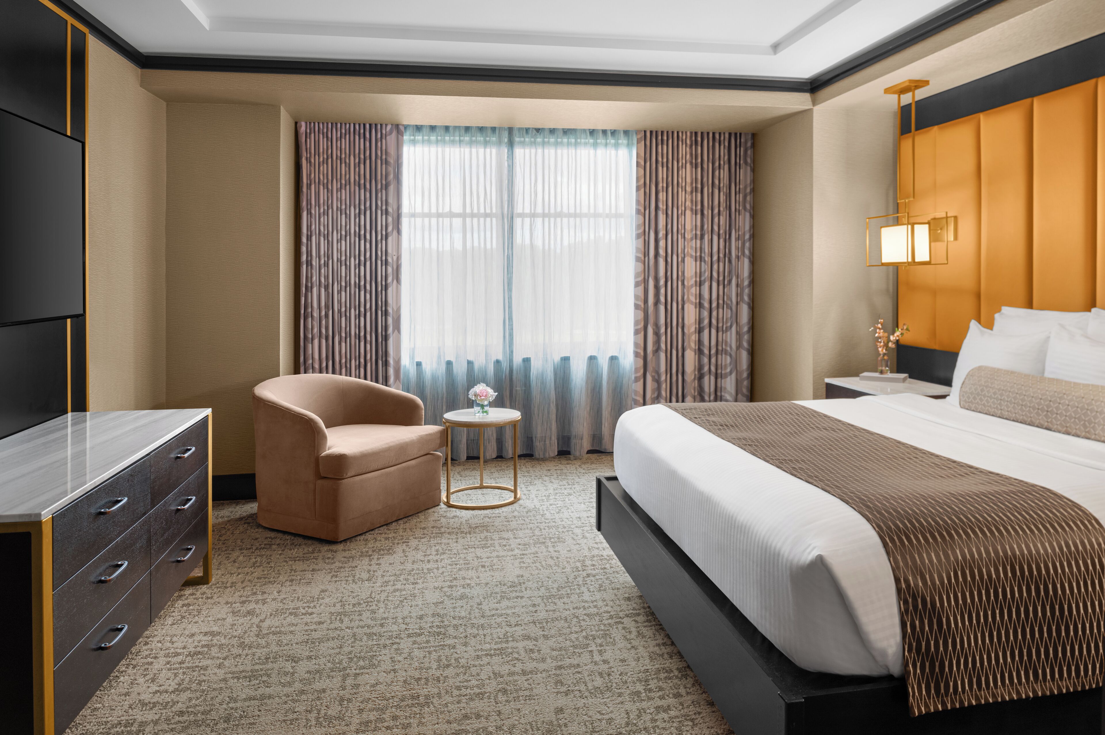 Une chambre d’hôtel avec un grand lit, un bureau, une chaise et une petite table sur laquelle se trouve un vase.