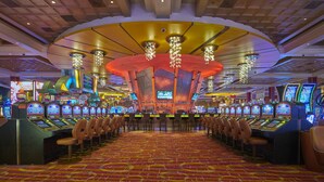 A casino with multiple slot machines, bar area, and a large chandelier.