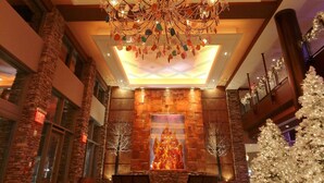 A lobby with a large chandelier, a fireplace, and a Christmas tree.