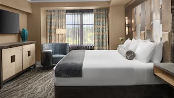 A hotel room with a large bed, a desk, a TV, and a view of the outdoors.