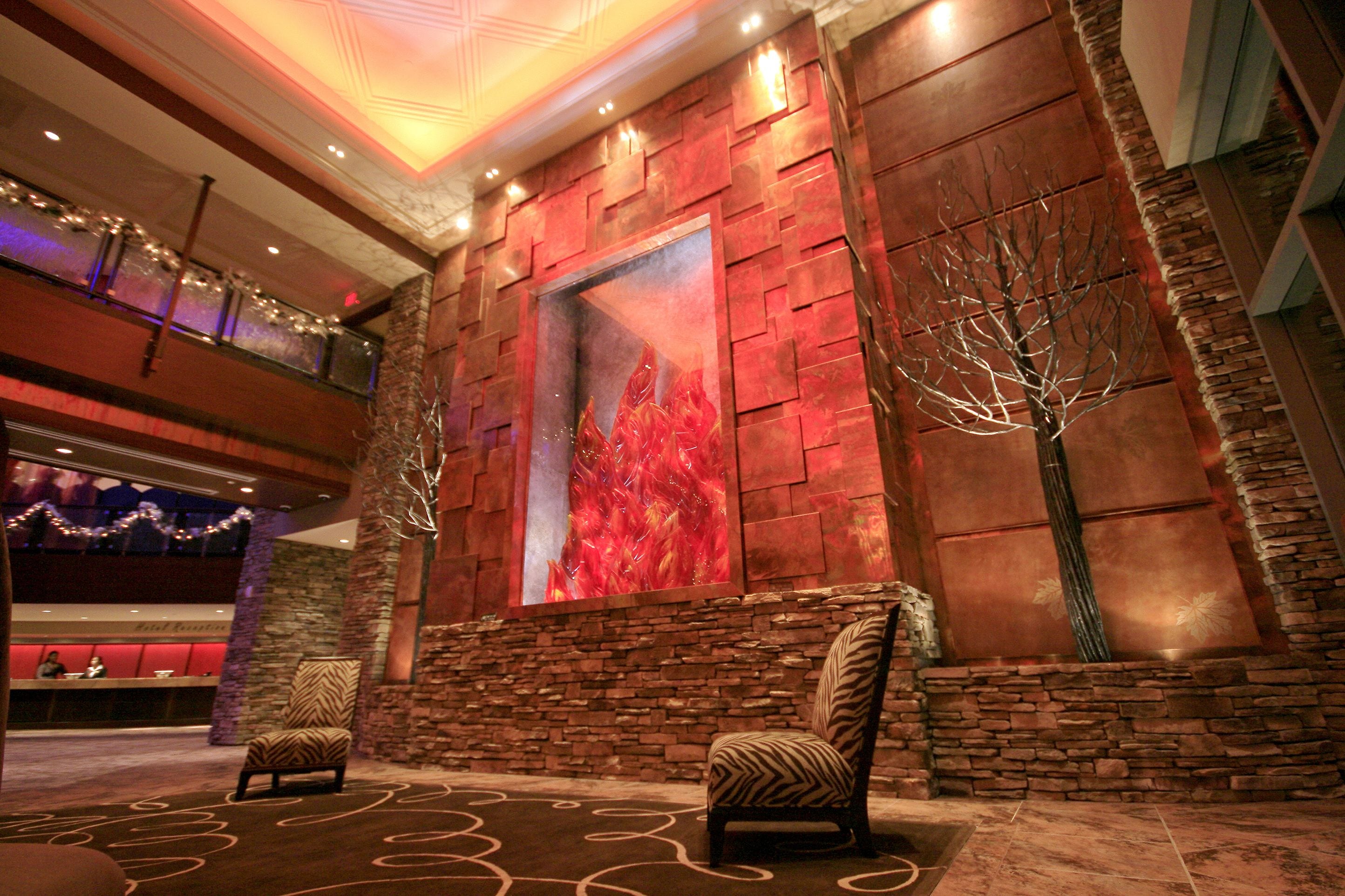 A lobby with a stone wall, a large abstract painting, and two patterned chairs.