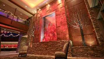 A lobby with a stone wall, a large abstract painting, and two patterned chairs.