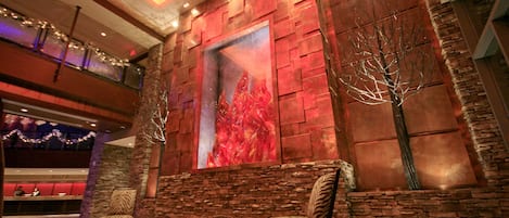 A lobby with a stone wall, a large abstract painting, and two patterned chairs.