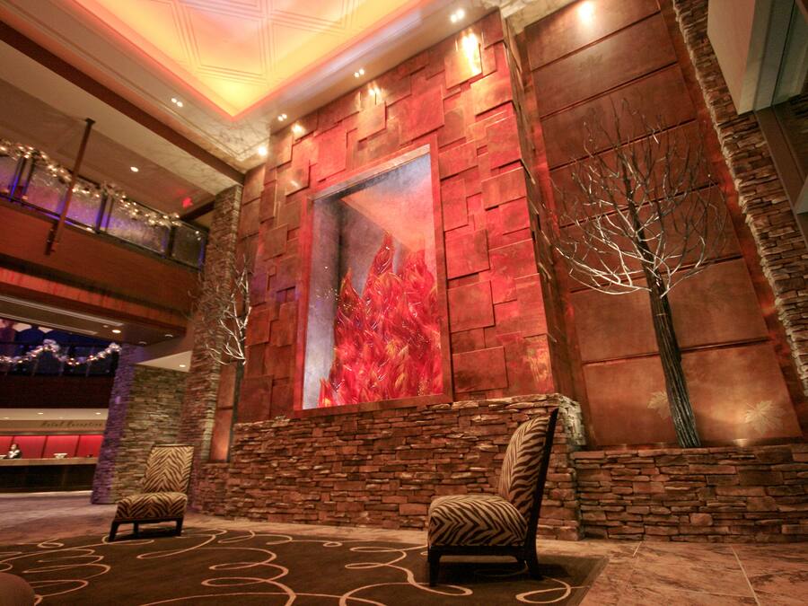 A lobby with a stone wall, a large abstract painting, and two patterned chairs.