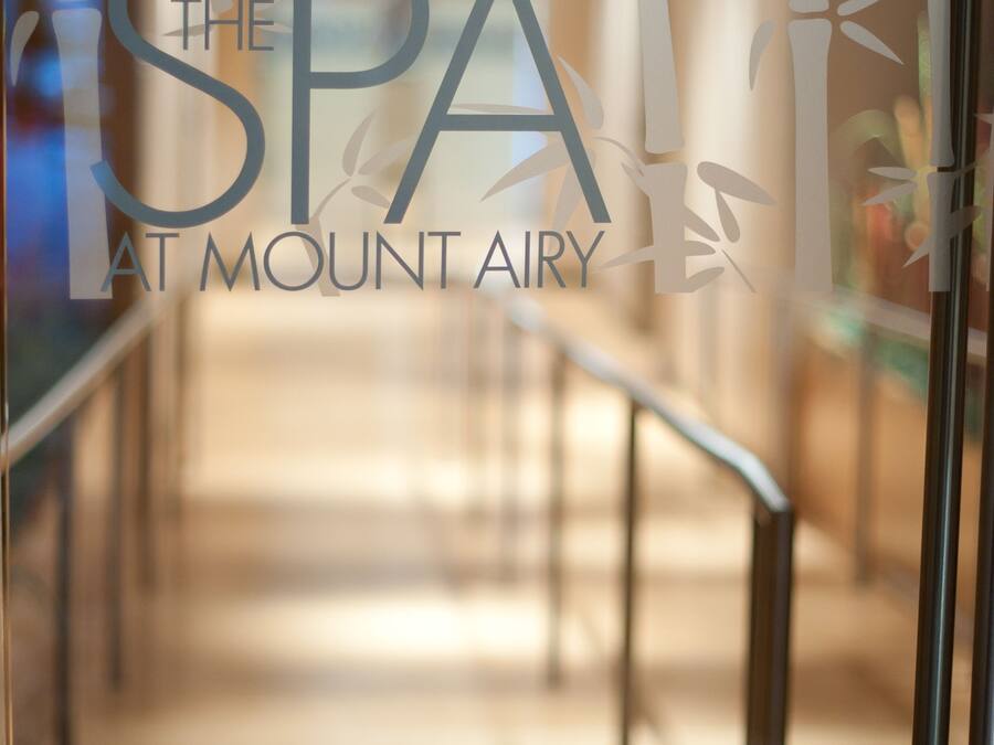 Un pasillo con un muro de vidrio que muestra el texto "The SPA at Mount Airy".