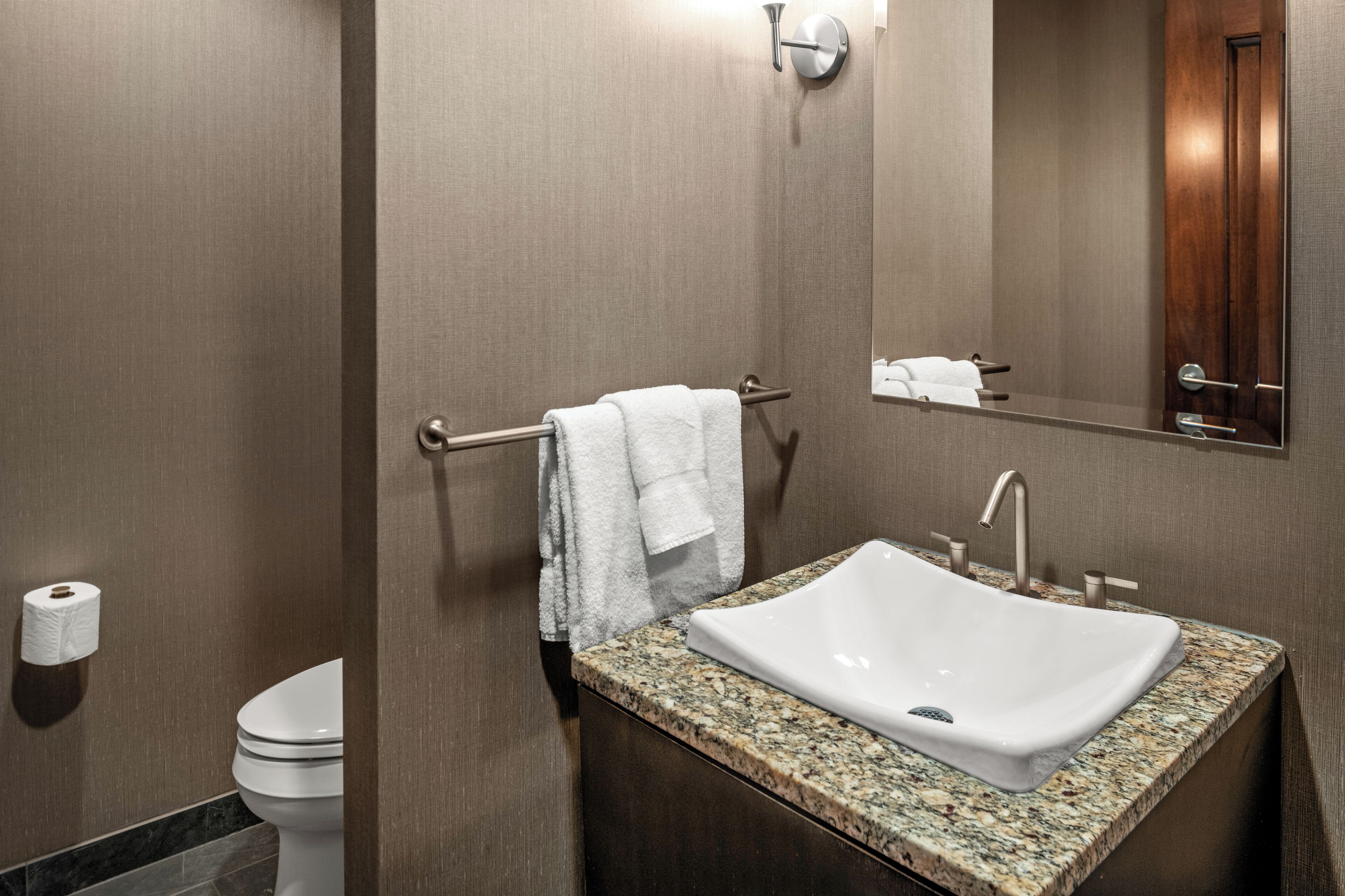 Ein modernes Badezimmer mit Marmorwaschtisch, Handtuchhalter, Toilette und Spiegel.