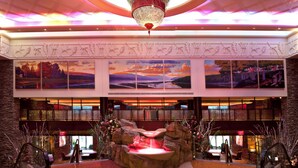 A lobby with a central water feature, multiple artworks, and a chandelier.