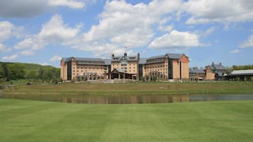 Un hotel grande con varias edificaciones, un patio central y un cuerpo de agua al frente.