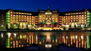 A large hotel with multiple floors, a central courtyard, and a reflection in the water.
