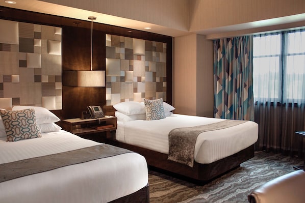 A hotel room with two beds, a nightstand with a phone, a wall with a geometric pattern, and a window with curtains. - Mount Airy Casino Resort - Adults Only 21+ (Mount Pocono)