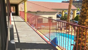 A balcony with a pool, a red railing, and a view of a building with a red roof. - America's Best Inn & Suites St. George (St. George)