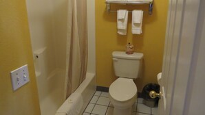 A bathroom with a bathtub, toilet, and a towel rack. - America's Best Inn & Suites St. George (St. George)